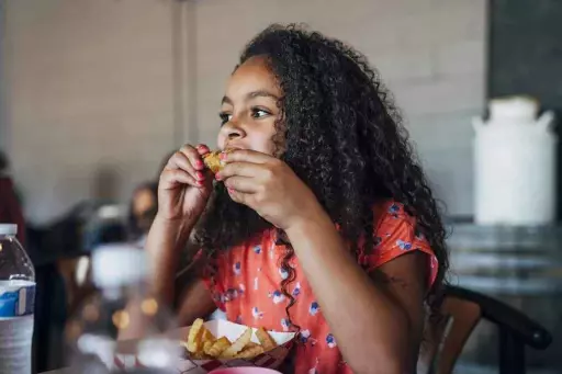 young girl eating chicken wing at wing heaven, a wing restaurant in clinton; best restaurants in Clinton