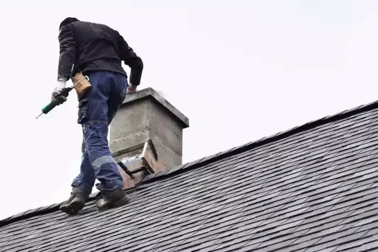 man on roof checking chimney during roof maintenance