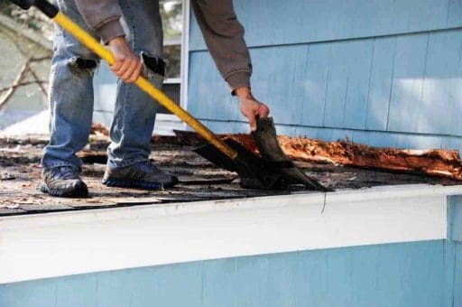 man on roof removing old shingles; roofing companies in columbia