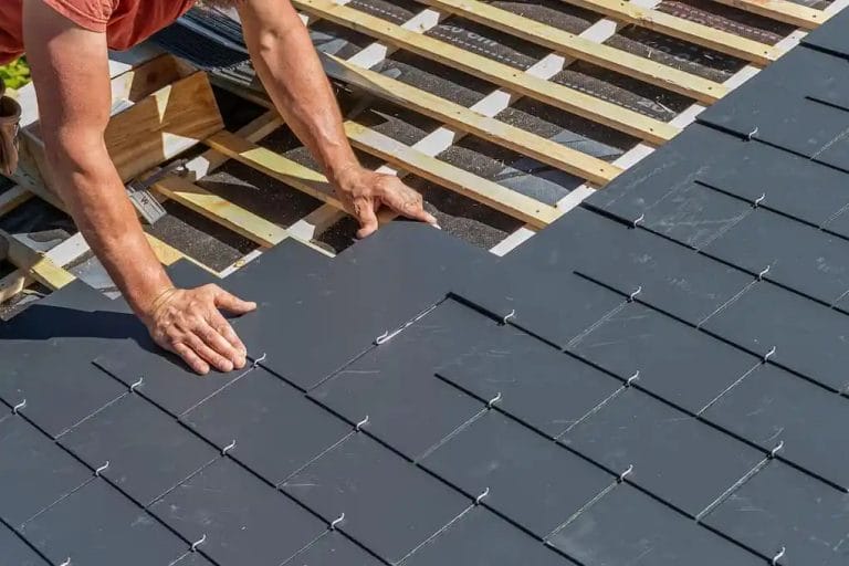 Craftsmen installing a slate roof on home after discussing tile roof cost