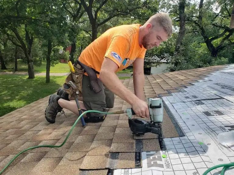 roofer showing homeowner how to repair shingles on a roof with a nail gun