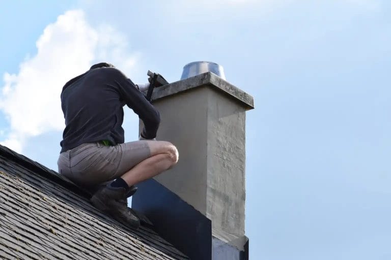 contractor installing roof flashing on a chimney