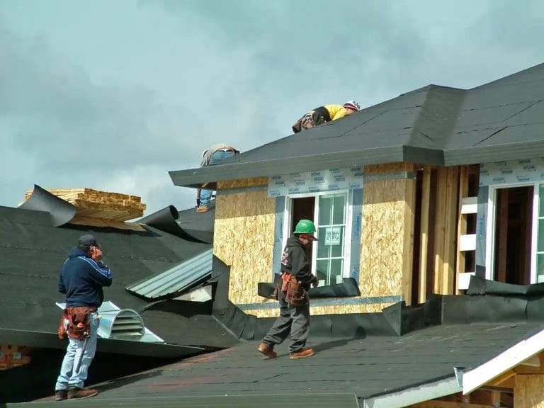 contractors installing roof underlayment on a house