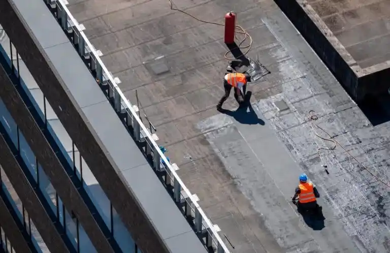 Birds eye view of a team of roofers completing commercial roof maintenance